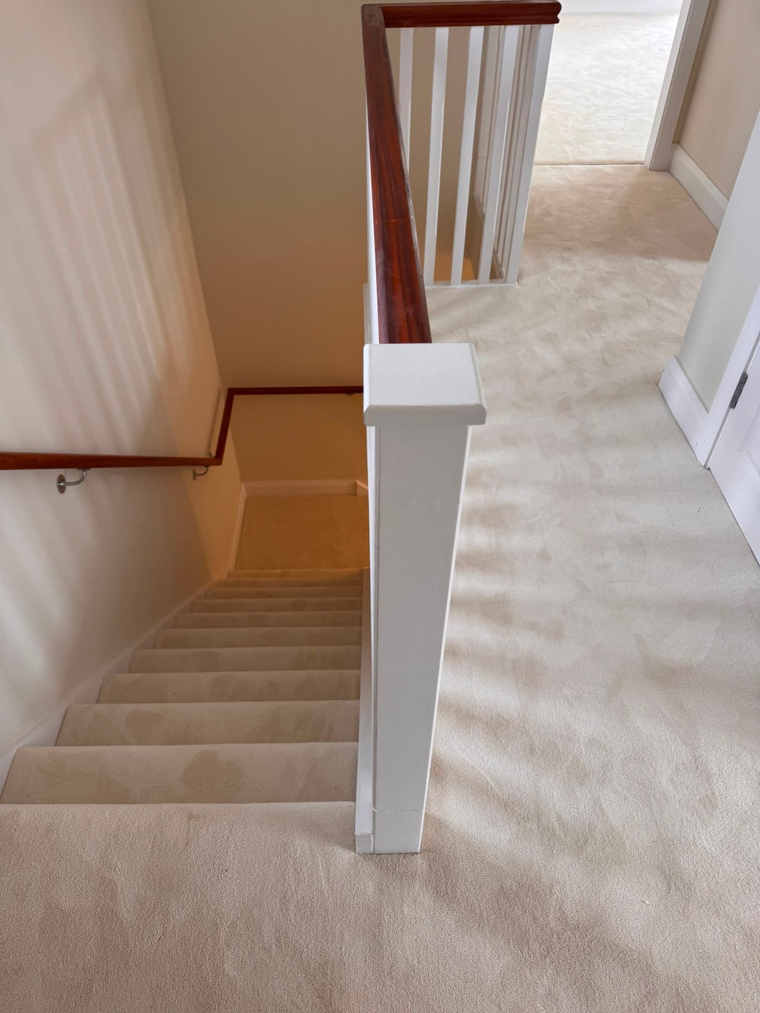 Cream carpet fitted on a staircase and landing with a wood handrail