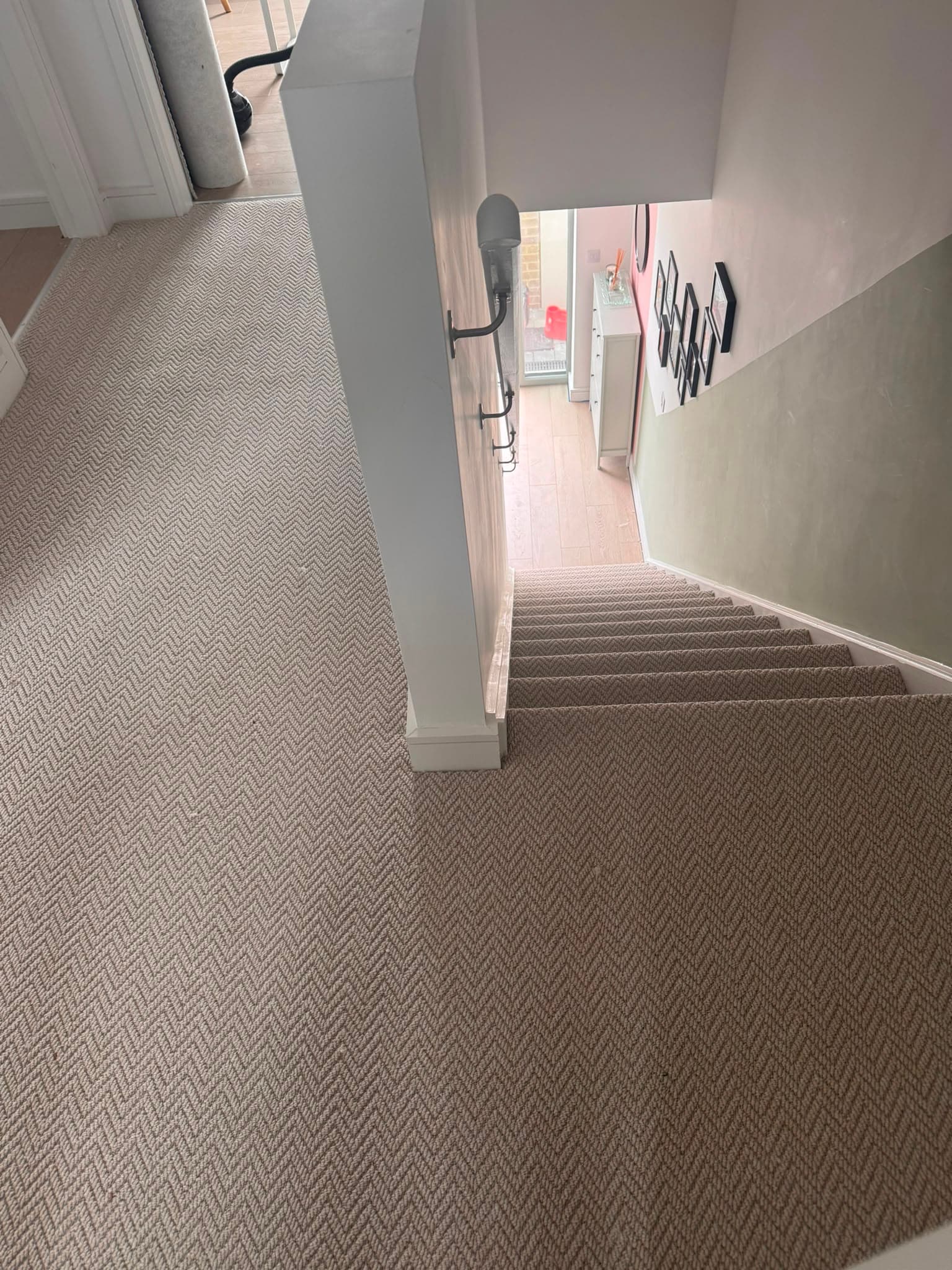 Black and cream herringbone-weave carpet fitted through a hallway and down a staircase