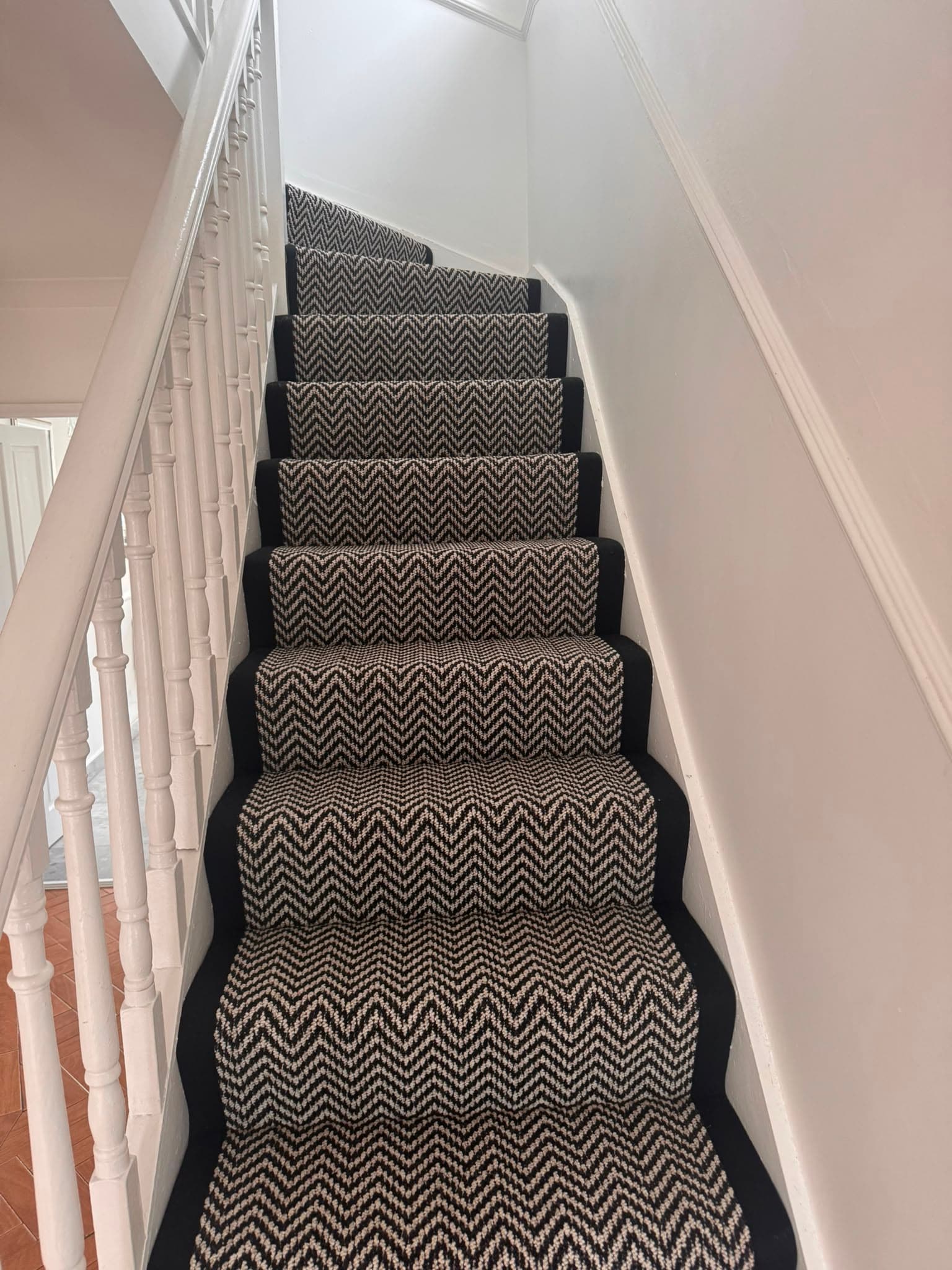 Black and cream chevron-pattern carpet fitted on a straight staircase