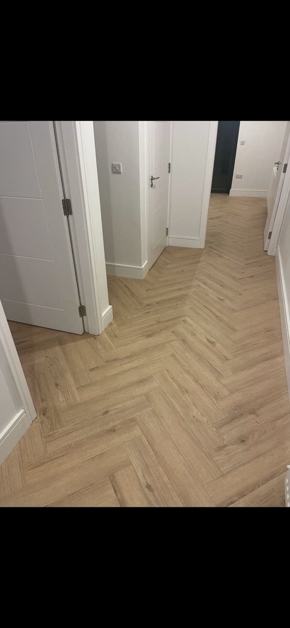 Herringbone-pattern laminate flooring fitted through a hallway by Philip B Flooring