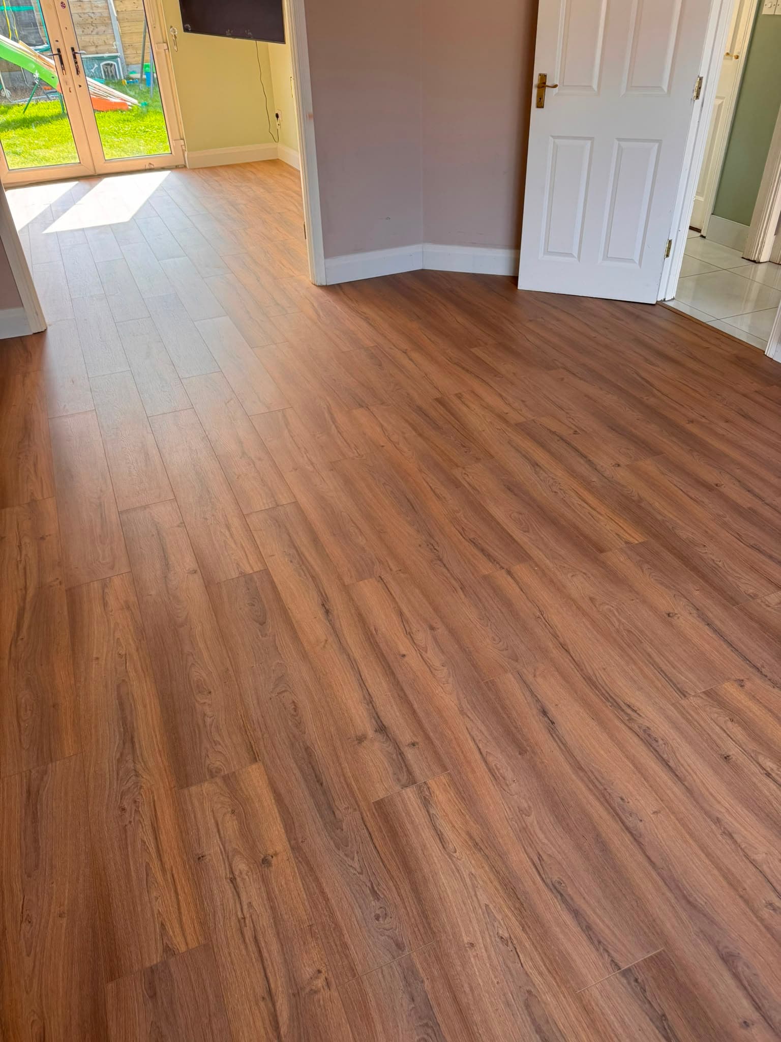 Bright open-plan room with laminate flooring fitted by Philip B Flooring, garden visible through patio doors